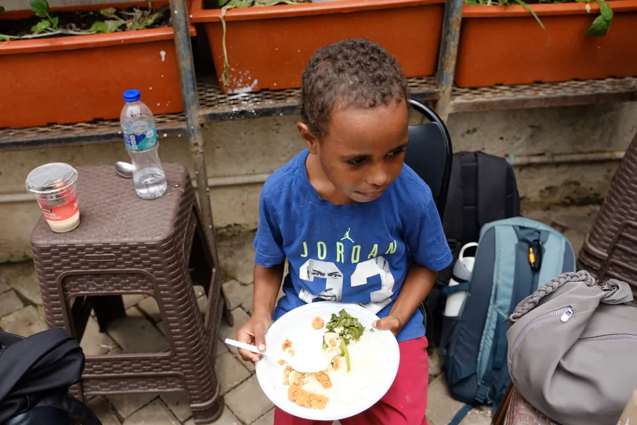Anak tersenyum memegang piring makan siangnya