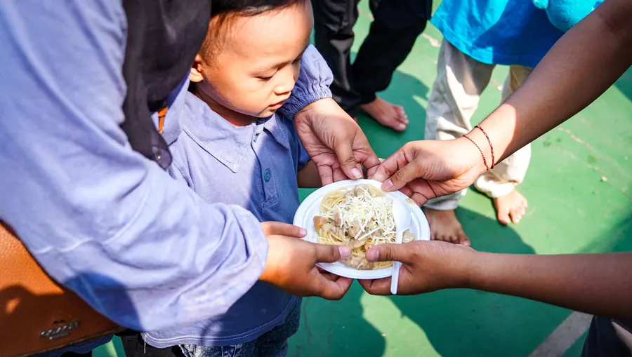 Seorang anak menerima piring makanan