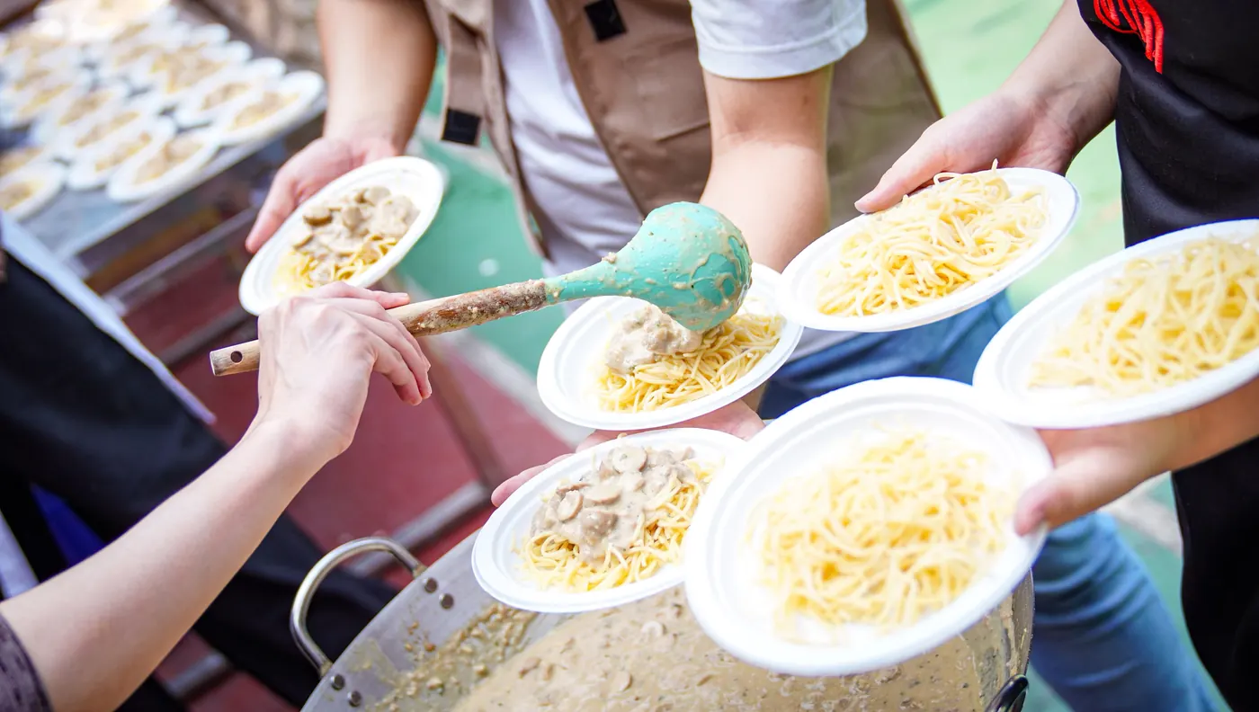 Tangan-tangan relawan membawa piring makanan